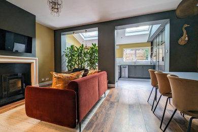 Example of a mid-sized eclectic dark wood floor living room design in Dublin with green walls and a stone fireplace