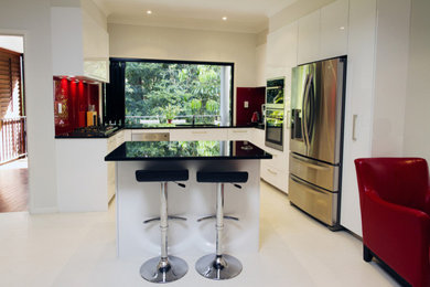 Design ideas for a mid-sized modern u-shaped open plan kitchen in Brisbane with an undermount sink, flat-panel cabinets, white cabinets, quartz benchtops, red splashback, glass sheet splashback, stainless steel appliances, porcelain floors, with island and white floor.