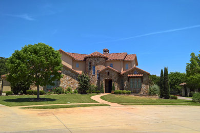 Example of a large tuscan house exterior design with a tile roof