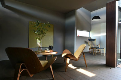 Imagen de salón abierto y gris minimalista pequeño con paredes grises, suelo de madera oscura, televisor colgado en la pared y suelo marrón