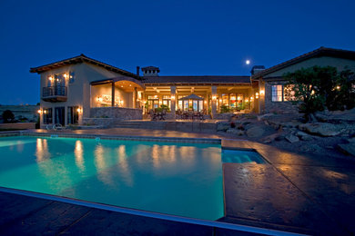 Example of a mid-sized tuscan backyard stamped concrete and rectangular lap pool design in Other