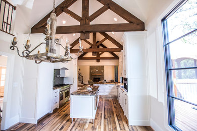 Kitchen - transitional light wood floor kitchen idea in Atlanta with an undermount sink, flat-panel cabinets, white cabinets, granite countertops, black backsplash, glass tile backsplash, stainless steel appliances and an island
