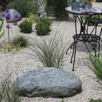 Kleiner Sitzplatz im Kiesgarten zwischen Gräsern und Stauden