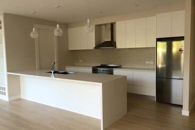 This is an example of a mid-sized galley eat-in kitchen in Melbourne with recessed-panel cabinets and with island.
