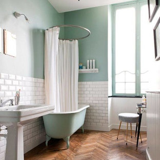 Foto di una stanza da bagno padronale moderna di medie dimensioni con vasca con piedi a zampa di leone, vasca/doccia, pareti blu, pavimento in legno massello medio e lavabo a colonna