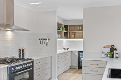 Inspiration for a large galley kitchen pantry in Perth with a single-bowl sink, granite benchtops, white splashback, ceramic splashback, stainless steel appliances, light hardwood floors, with island, brown floor and white benchtop.