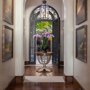 This is an example of a mediterranean entry hall in Orange County with medium hardwood floors, a single front door, a metal front door and white walls.