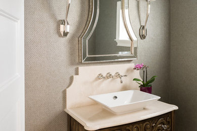 This is an example of a small transitional powder room in New York with a one-piece toilet, grey walls, marble floors, a vessel sink and marble benchtops.