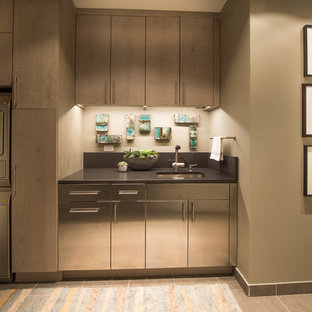 Large modern utility room in Chicago with stainless steel cabinets, beige walls, porcelain flooring and a stacked washer and dryer.