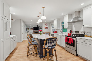 Kitchen - transitional galley light wood floor and beige floor kitchen idea in Philadelphia with an undermount sink, recessed-panel cabinets, white cabinets, white backsplash, subway tile backsplash, stainless steel appliances, an island and white countertops