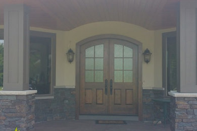 Modelo de puerta principal mediterránea grande con paredes blancas, suelo de madera oscura, puerta doble, puerta de madera oscura y suelo marrón