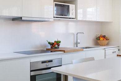 Ejemplo de cocina comedor minimalista de tamaño medio con fregadero bajoencimera, armarios con paneles lisos, puertas de armario blancas, encimera de cuarzo compacto, salpicadero blanco, electrodomésticos de acero inoxidable, suelo de baldosas de cerámica, península, suelo beige y encimeras blancas