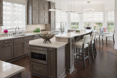 Huge trendy u-shaped dark wood floor and brown floor eat-in kitchen photo in Newark with an undermount sink, gray cabinets, white backsplash, marble backsplash, stainless steel appliances, an island, quartz countertops, recessed-panel cabinets and white countertops