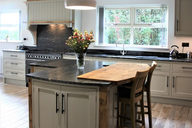 Imagen de cocina comedor contemporánea de tamaño medio con fregadero encastrado, armarios estilo shaker, encimera de granito, salpicadero negro, electrodomésticos negros, suelo de baldosas de porcelana, una isla y suelo marrón