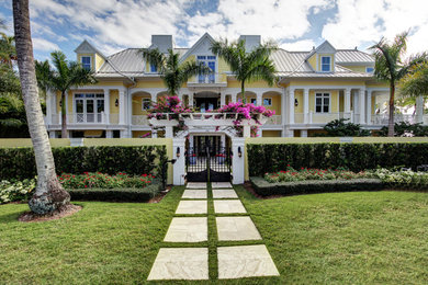 Example of a huge beach style yellow three-story wood exterior home design in Miami