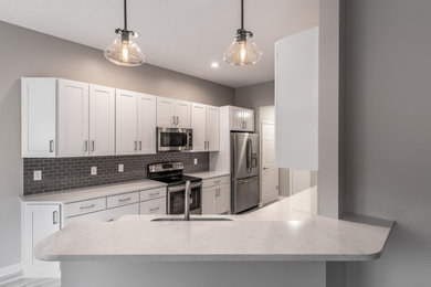Mid-sized transitional galley porcelain tile and multicolored floor eat-in kitchen photo in Other with recessed-panel cabinets, white cabinets, quartz countertops, a peninsula, white countertops, an undermount sink, gray backsplash, stainless steel appliances and ceramic backsplash