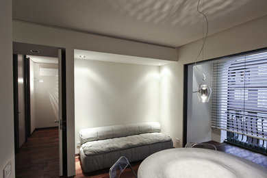 Esempio di una piccola camera da letto contemporanea con pareti bianche, parquet scuro e pavimento marrone