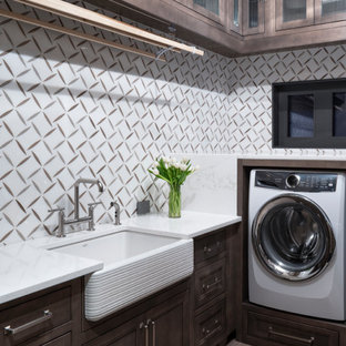 Design ideas for a medium sized classic u-shaped separated utility room in Denver with a belfast sink, beaded cabinets, medium wood cabinets, engineered stone countertops, white walls, porcelain flooring, an integrated washer and dryer, brown floors and white worktops.