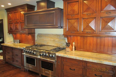 Inspiration for a large galley dark wood floor enclosed kitchen remodel in Chicago with an integrated sink, raised-panel cabinets, medium tone wood cabinets, granite countertops, beige backsplash, stainless steel appliances and a peninsula