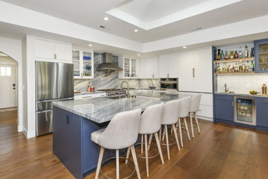 Inspiration for a contemporary l-shaped dark wood floor, brown floor and tray ceiling kitchen remodel in San Francisco with an undermount sink, flat-panel cabinets, white cabinets, gray backsplash, stone slab backsplash, stainless steel appliances, an island and gray countertops