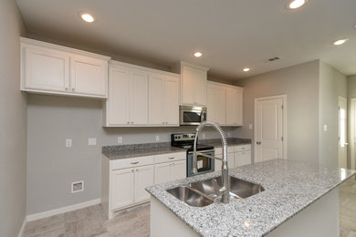 This is an example of a mid-sized transitional u-shaped eat-in kitchen in Dallas with a double-bowl sink, flat-panel cabinets, white cabinets, granite benchtops, multi-coloured splashback, stainless steel appliances, ceramic floors and with island.