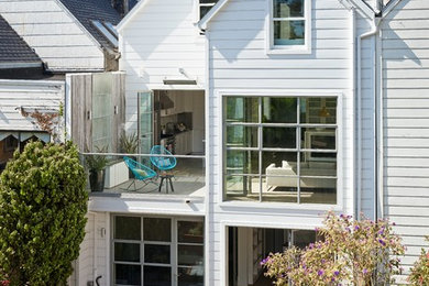 This is an example of a transitional three-storey white townhouse exterior in San Francisco with a gable roof.