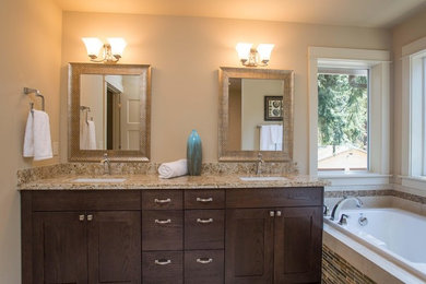 Drop-in bathtub - traditional beige tile drop-in bathtub idea in Portland with dark wood cabinets, granite countertops and beige walls
