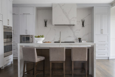 Kitchen - contemporary l-shaped dark wood floor and brown floor kitchen idea in New York with shaker cabinets, white cabinets, white backsplash, stone slab backsplash, stainless steel appliances, an island and white countertops