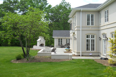 Large traditional gray two-story stucco house exterior idea in Other with a hip roof and a shingle roof
