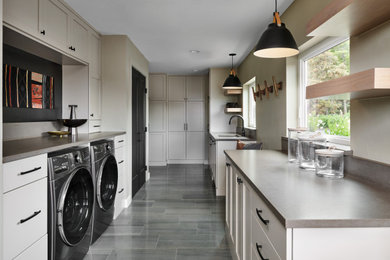 Utility room - large transitional l-shaped porcelain tile utility room idea in Denver with an undermount sink, recessed-panel cabinets, beige cabinets, quartz countertops, gray backsplash, quartz backsplash, beige walls, a side-by-side washer/dryer and gray countertops