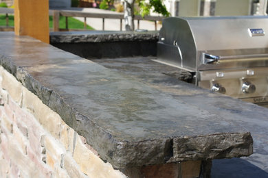 Inspiration for a rustic backyard brick patio kitchen remodel in Denver with a pergola