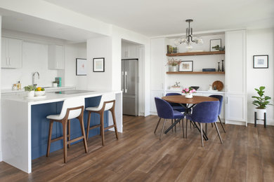 Small trendy l-shaped vinyl floor and brown floor eat-in kitchen photo in Toronto with an undermount sink, shaker cabinets, white cabinets, quartz countertops, white backsplash, quartz backsplash, stainless steel appliances, an island and white countertops