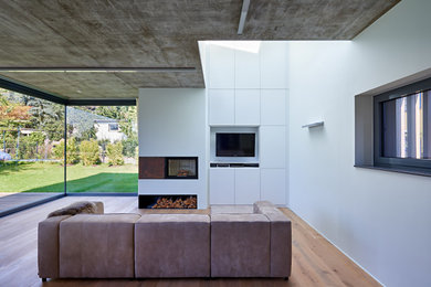 Mittelgroßes, Offenes Modernes Wohnzimmer mit weißer Wandfarbe, hellem Holzboden, Kaminofen, verputzter Kaminumrandung, TV-Wand und beigem Boden