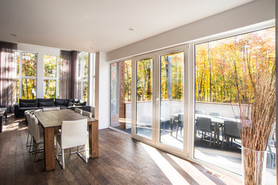 This is an example of a mid-sized contemporary open plan dining in Montreal with white walls, dark hardwood floors, no fireplace and brown floor.