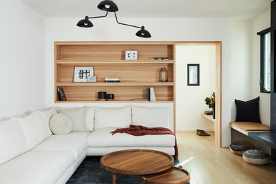 Example of a trendy light wood floor family room design in Los Angeles with white walls and a stone fireplace