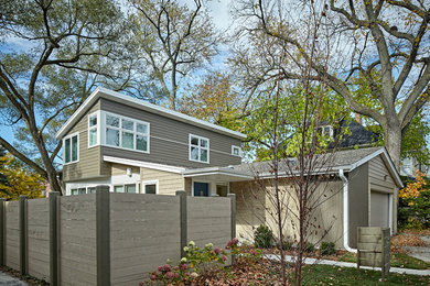 Photo of a mid-sized midcentury split-level beige exterior in Chicago with concrete fiberboard siding and a shed roof.