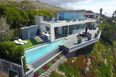 Pool house - modern backyard custom-shaped infinity pool house idea