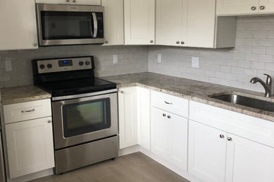 Enclosed kitchen - mid-sized l-shaped ceramic tile and beige floor enclosed kitchen idea in DC Metro with an undermount sink, white cabinets, granite countertops, gray backsplash, glass tile backsplash, stainless steel appliances, no island and brown countertops