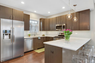 Open concept kitchen - mid-sized modern u-shaped medium tone wood floor open concept kitchen idea in Chicago with an undermount sink, flat-panel cabinets, dark wood cabinets, quartz countertops, white backsplash, glass tile backsplash, stainless steel appliances and a peninsula
