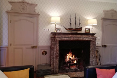 Foto de salón para visitas tradicional grande con todas las chimeneas, piedra de revestimiento, televisor retractable y papel pintado