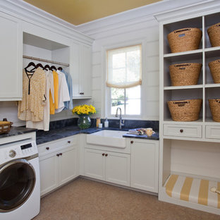他の地域のトランジショナルスタイルのおしゃれな洗濯室 (エプロンフロントシンク、シェーカースタイル扉のキャビネット、白いキャビネット、左右配置の洗濯機・乾燥機、コルクフローリング、黒いキッチンカウンター) の写真