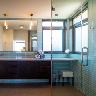 Aménagement d'une salle de bain principale contemporaine de taille moyenne avec un placard à porte plane, des portes de placard noires, une douche d'angle, un carrelage bleu, un carrelage en pâte de verre, un mur bleu, un sol en bambou, un lavabo intégré, un sol marron, une cabine de douche à porte battante et un plan de toilette blanc.