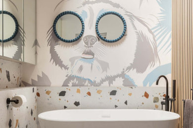 This is an example of a medium sized contemporary grey and cream bathroom in London with a freestanding bath, a wall mounted toilet, multi-coloured tiles, white walls, terrazzo flooring, multi-coloured floors, a feature wall and wallpapered walls.