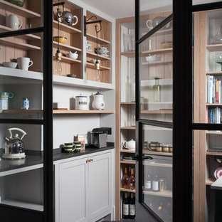 Cette image montre une arrière-cuisine nordique avec un placard sans porte, des portes de placard blanches, une crédence blanche, une crédence en bois et aucun îlot.