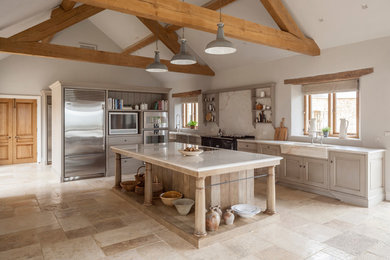 Large country galley open plan kitchen in Gloucestershire with a single-bowl sink, raised-panel cabinets, marble benchtops, white splashback, stone slab splashback, stainless steel appliances, limestone floors, with island and grey cabinets.