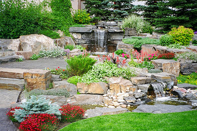 This is an example of a backyard patio in Other with a water feature, natural stone pavers and no cover.