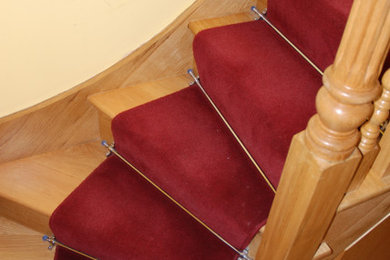 ロンドンにある低価格の小さなシャビーシック調のおしゃれなかね折れ階段 (フローリングの蹴込み板、木材の手すり、板張り壁) の写真