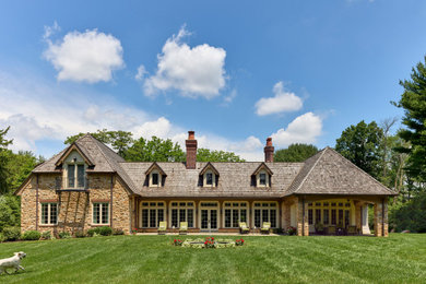 Foto de fachada de casa beige y marrón clásica de dos plantas con revestimiento de piedra, tejado a la holandesa, tejado de teja de madera y teja