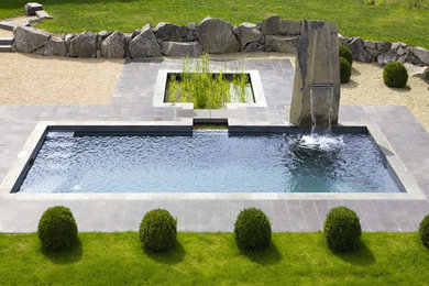 Design ideas for a large contemporary backyard custom-shaped aboveground pool in Berlin with concrete slab.