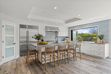 Inspiration for a huge coastal l-shaped vinyl floor, gray floor and tray ceiling eat-in kitchen remodel in San Francisco with an undermount sink, recessed-panel cabinets, white cabinets, quartzite countertops, blue backsplash, porcelain backsplash, stainless steel appliances, an island and multicolored countertops